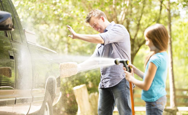 Father and daughter wash the family car on their driveway