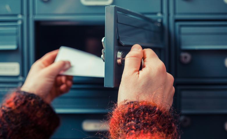 Hands opening a mailbox and pulling out a letter