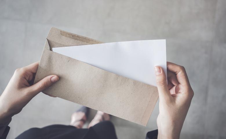 Woman holding white paper in envelope