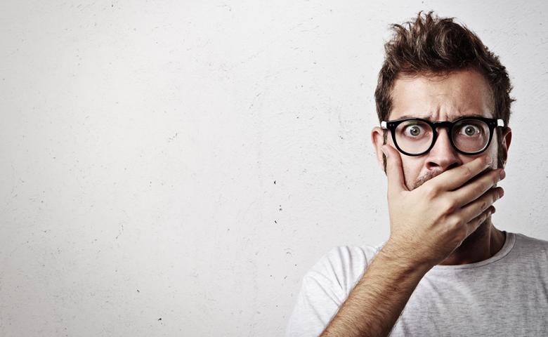 Man with shocked look on his face, with his hand covering his mouth