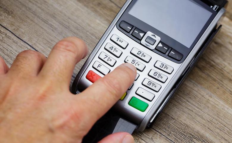 Closeup of a man&#039;s hand typing a code on a payment terminal