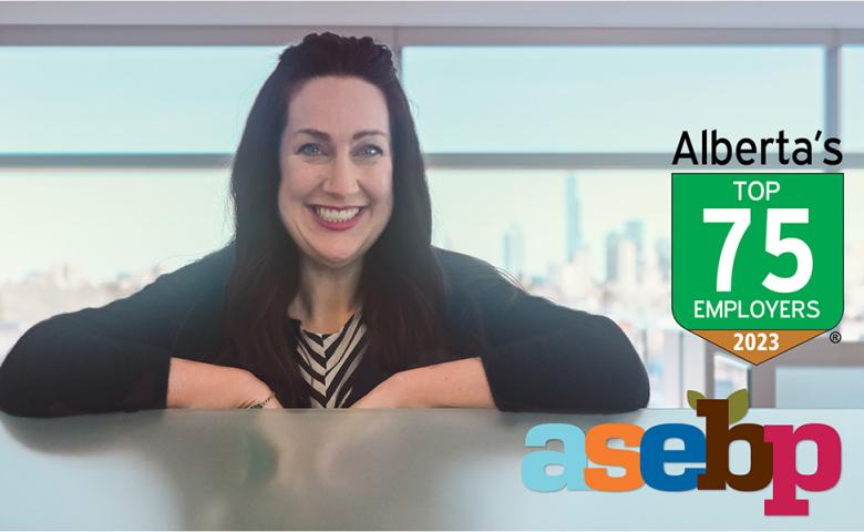  Employee smiling in front of window at ASEBP. Image includes Alberta’s Top Employers 2023 and ASEBP logos in the bottom right corner. 